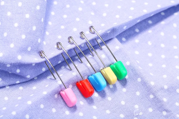 Safety pins on fabric background — Stock Photo, Image