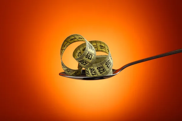 Measuring tape in silver spoon on orange background — Stock Photo, Image