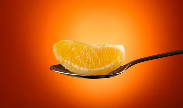 Fatia de laranja em colher de prata no fundo laranja — Fotografia de Stock