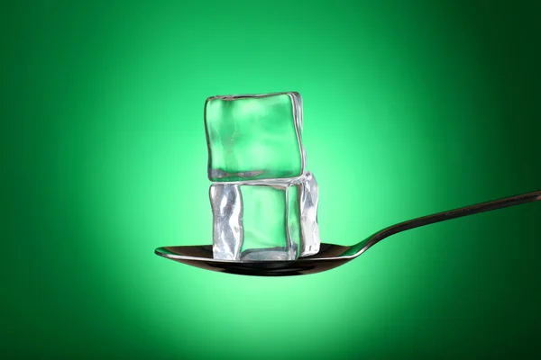 Cubos de hielo en cuchara de plata sobre fondo verde —  Fotos de Stock