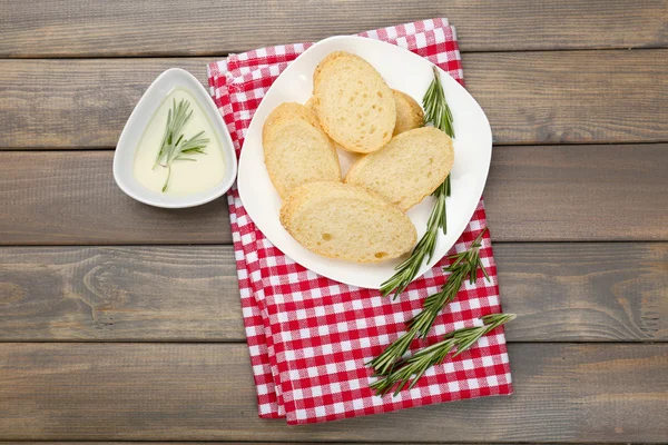 Pão fresco com azeite e alecrim sobre mesa de madeira — Fotografia de Stock