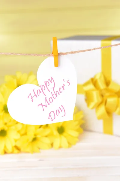 Happy Mothers Day message written on paper heart with flowers on yellow background — Stock Photo, Image