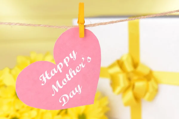 Happy Mothers Day message written on paper heart with flowers on yellow background — Stock Photo, Image