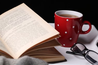 Kitap ve kareli koyu arka plan üzerinde masada sıcak çay