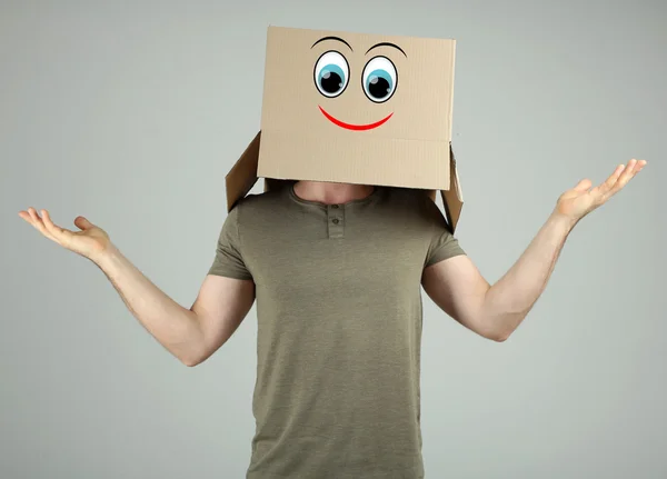 Άνθρωπος με κουτί από χαρτόνι στο κεφάλι του σε γκρίζο φόντο — Φωτογραφία Αρχείου