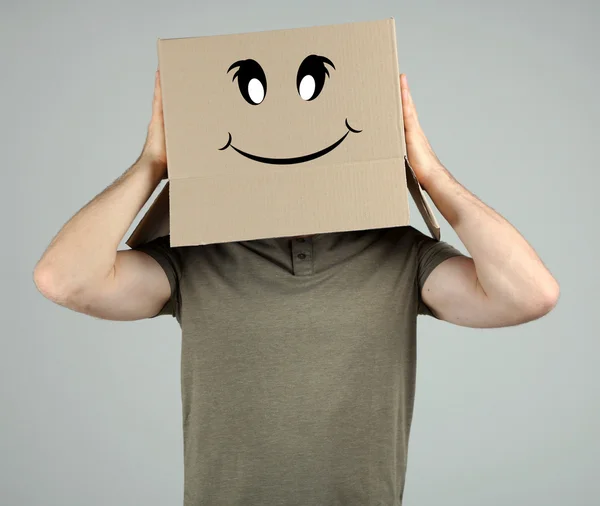 Hombre con caja de cartón en la cabeza sobre fondo gris — Foto de Stock