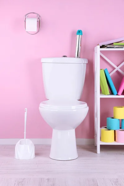 Bol de toilette blanc et support avec livres, sur fond de mur de couleur — Photo