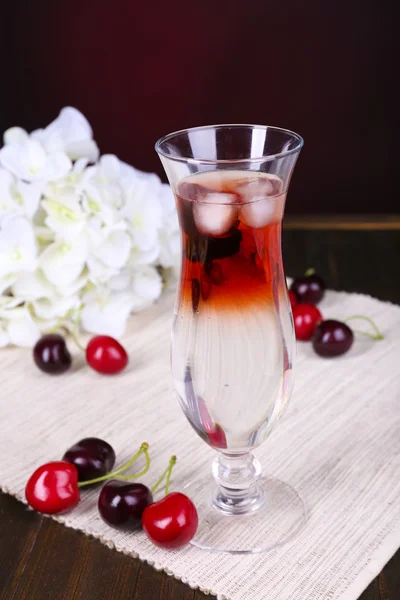 Glass of cocktail on table on dark red background — Stock Photo, Image