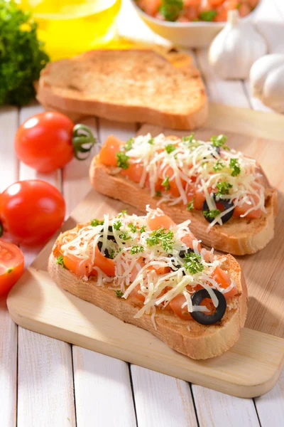 Deliciosa bruschetta con tomates en la tabla de cortar de cerca — Foto de Stock