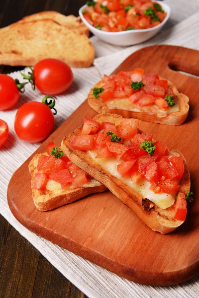 Deliciosa bruschetta con tomates en la tabla de cortar de cerca —  Fotos de Stock