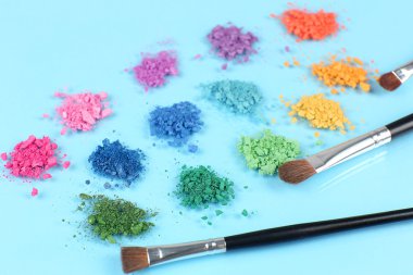 Gökkuşağı göz farı ve profesyonel makyaj fırçası mavi zemin üzerine ezilmiş