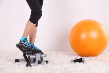 Young beautiful fitness girl exercising on stepper in gym