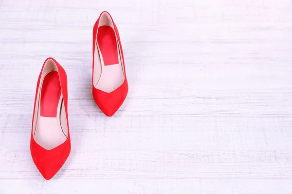 Belle scarpe rosse femminili, su sfondo di legno — Foto Stock