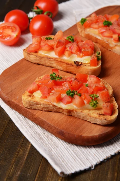 Delicious bruschetta with tomatoes on cutting board close-up — Stock Photo, Image