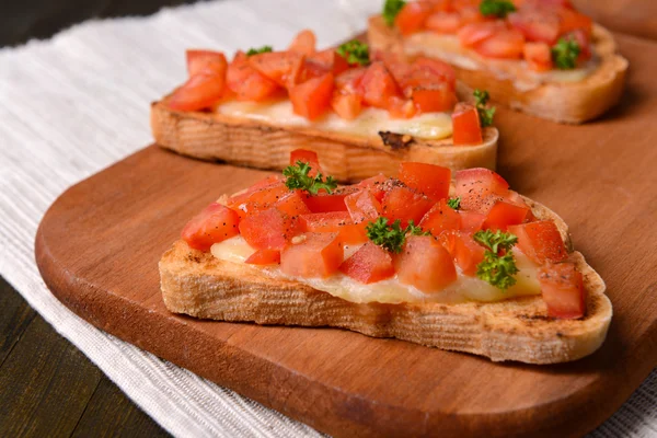 Heerlijke bruschetta met tomaten op snijplank close-up — Stockfoto