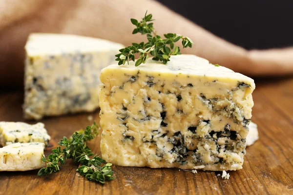 Tasty blue cheese with thyme, on wooden table — Stock Photo, Image