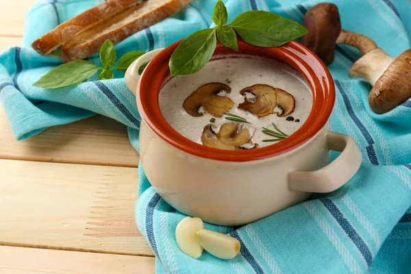 Mushroom soup in pot, on napkin,  on wooden background — Stock Photo, Image