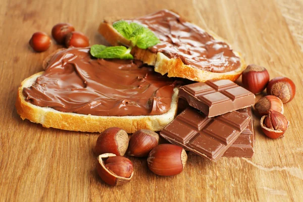 Bröd med söt choklad hasselnöt sprida på trä bakgrund — Stockfoto