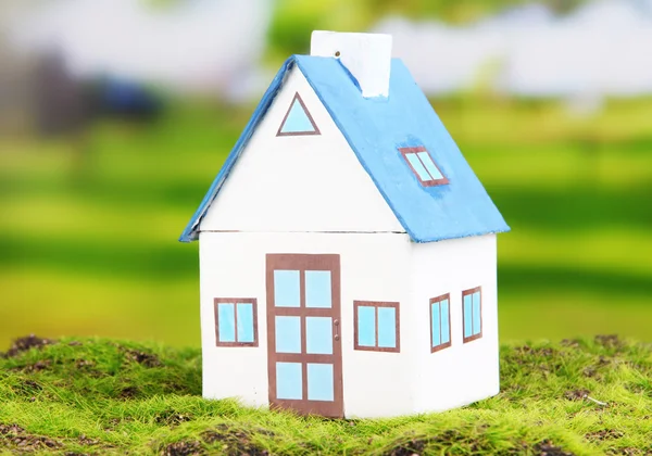 Little house and paper people on green grass, on bright background — Stock Photo, Image