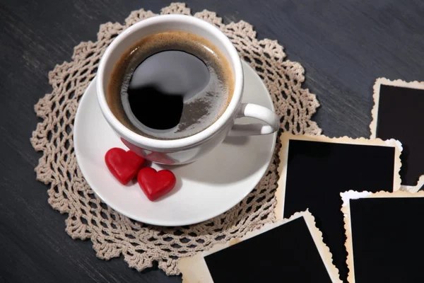 Composizione con tazza di caffè, cuori decorativi e vecchie foto in bianco, su sfondo di legno — Foto Stock