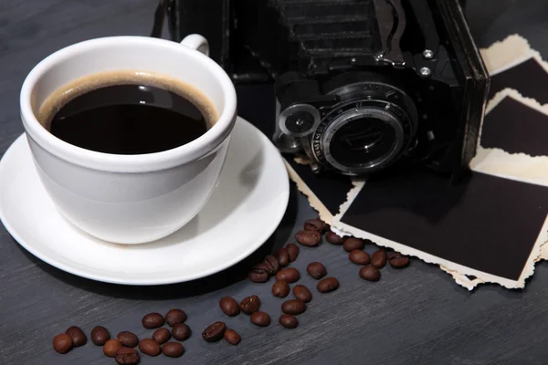 Šálek kávy, vinobraní fotoaparát a prázdné fotografie, na dřevěné pozadí — Stock fotografie