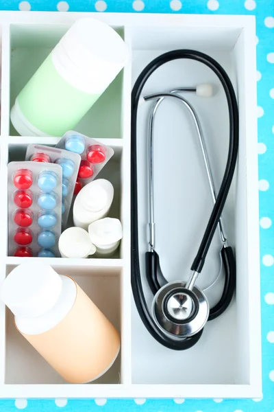 Medicinska piller, stetoskop, ampuller i trälåda, på färgbakgrund — Stockfoto