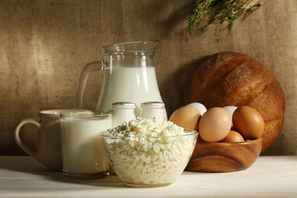 Produtos lácteos saborosos na mesa de madeira, no fundo de saque — Fotografia de Stock