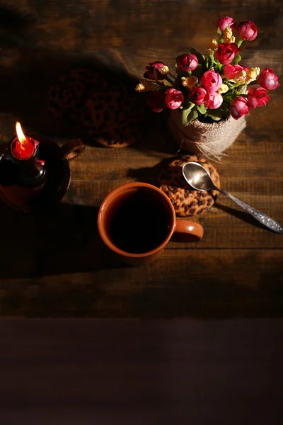 Skład z kubkiem gorącego napoju, świeca i kwiaty na tle drewniany stół — Zdjęcie stockowe