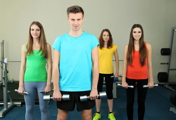 Jóvenes hermosas personas comprometidas con pesas en el gimnasio —  Fotos de Stock