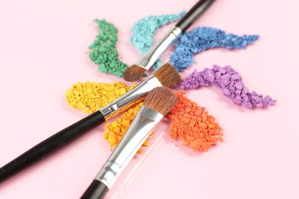 Rainbow crushed eyeshadow and professional make-up brush on pink background — Stock Photo, Image