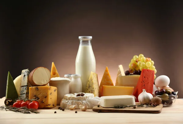 Tasty dairy products on wooden table, on dark background — Stock Photo, Image