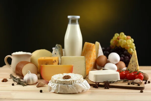 Produtos lácteos saborosos na mesa de madeira, no fundo escuro — Fotografia de Stock