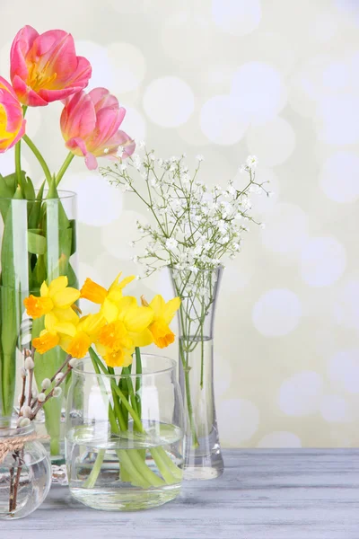 Krásné květiny v proutěném koši, na barevné tkaniny a dřevěné pozadí — Stock fotografie