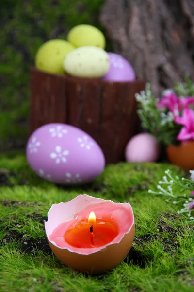 Composition conceptuelle de Pâques. Bougie brûlante dans l'oeuf, oeufs de Pâques et fleurs sur fond d'herbe verte, gros plan — Photo