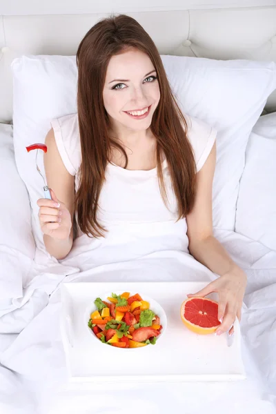 Unga vackra kvinnan i sängen med lätt frukost — Stockfoto