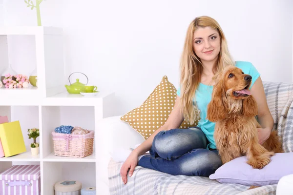 Beautiful young woman with cocker spaniel on couch in room — Stock Photo, Image