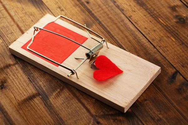 Mousetrap with heart on wooden background — Stock Photo, Image