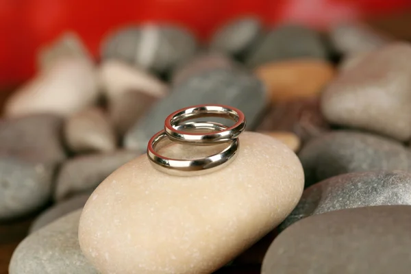 Anéis de casamento em rochas no fundo vermelho — Fotografia de Stock