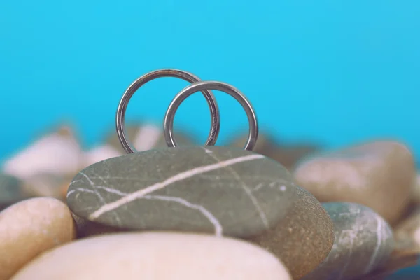 Snubní prsteny na skalách na modrém pozadí — Stock fotografie
