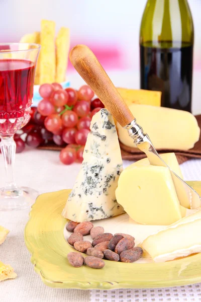 Assiette au fromage assortie, verre de raisin et de vin sur la table, sur fond clair — Photo