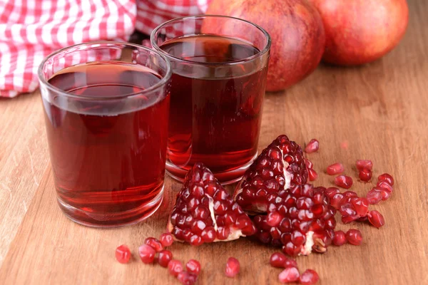 Ripe pomegranates with juice on table close-up — Stock Photo, Image