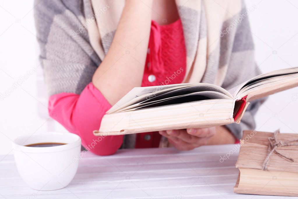 Woman reading book and  drink coffee or tea, close-up