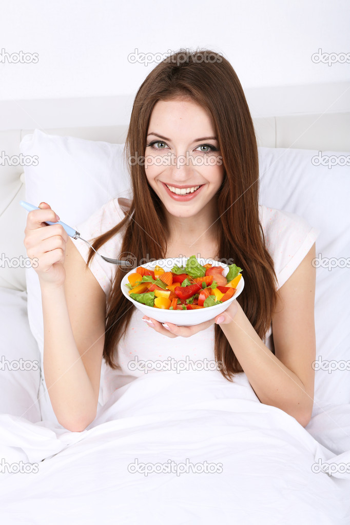 Young beautiful woman in bed with light breakfast 