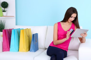 alışveriş torbaları Divan mavi zemin üzerine ile güzel bir genç kadın holding tablet
