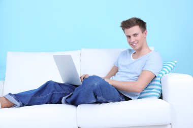 kanepe adam yalanla mavi arka plan üstünde laptop
