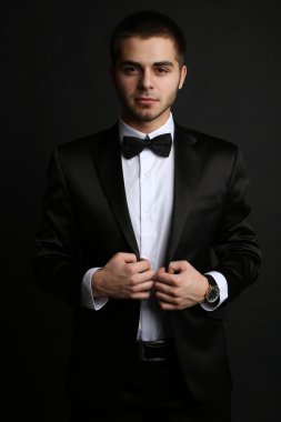 Handsome young man in suit on dark background clipart