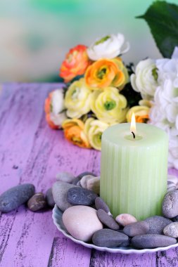 spa taşlar, mum ve ışık arka plan üzerinde renkli ahşap masaya çiçek kompozisyonu