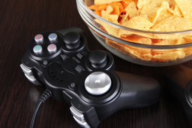 siyah oyun denetleyicileri ve aperatifler ahşap arka plan üzerine bir kase