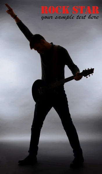 Kytarista silueta na tmavě šedém pozadí — Stock fotografie