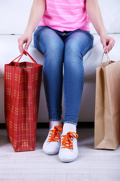 Kvinna sitter på soffan med väskor shopping närbild — Stockfoto